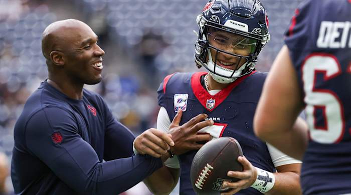 DeMeco Ryans laughs as he grabs C.J. Stroud, who holds the ball in one hand.